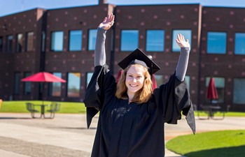 Student in cap and gown with arms in the air