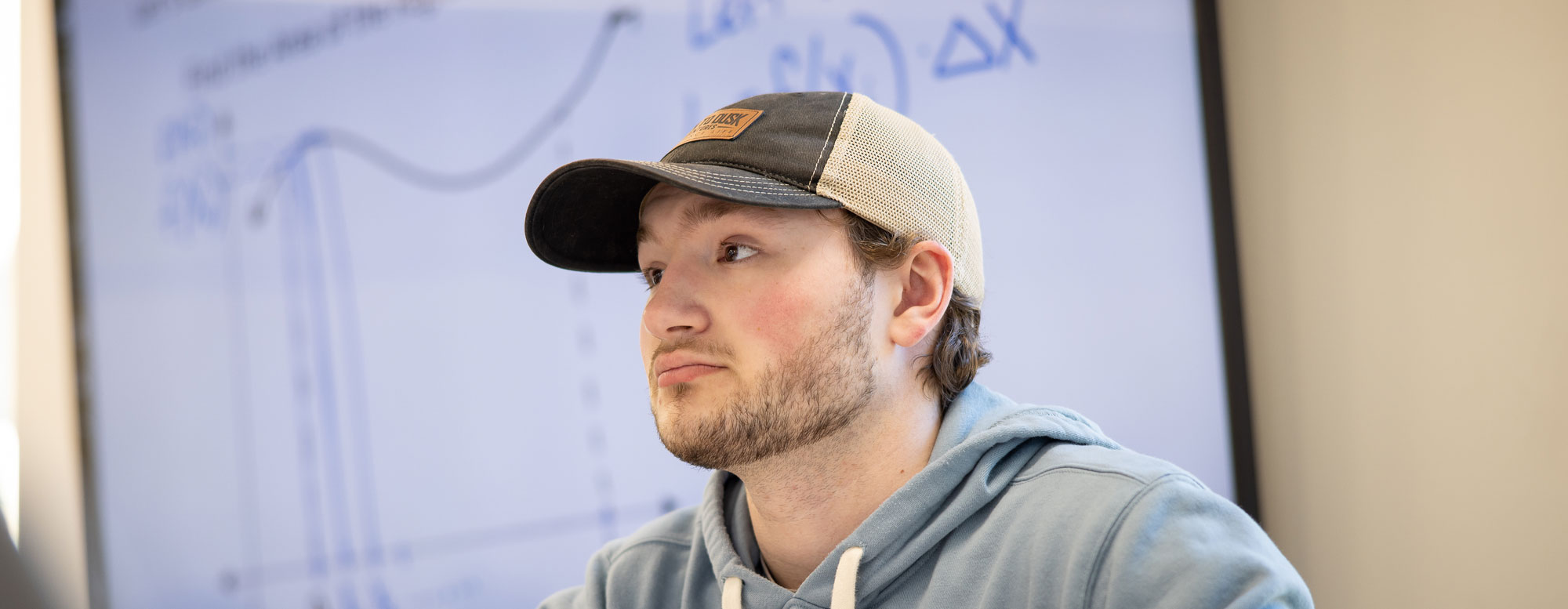 Student reviewing a plotted graph on a classroom display in an accounting and finance course.