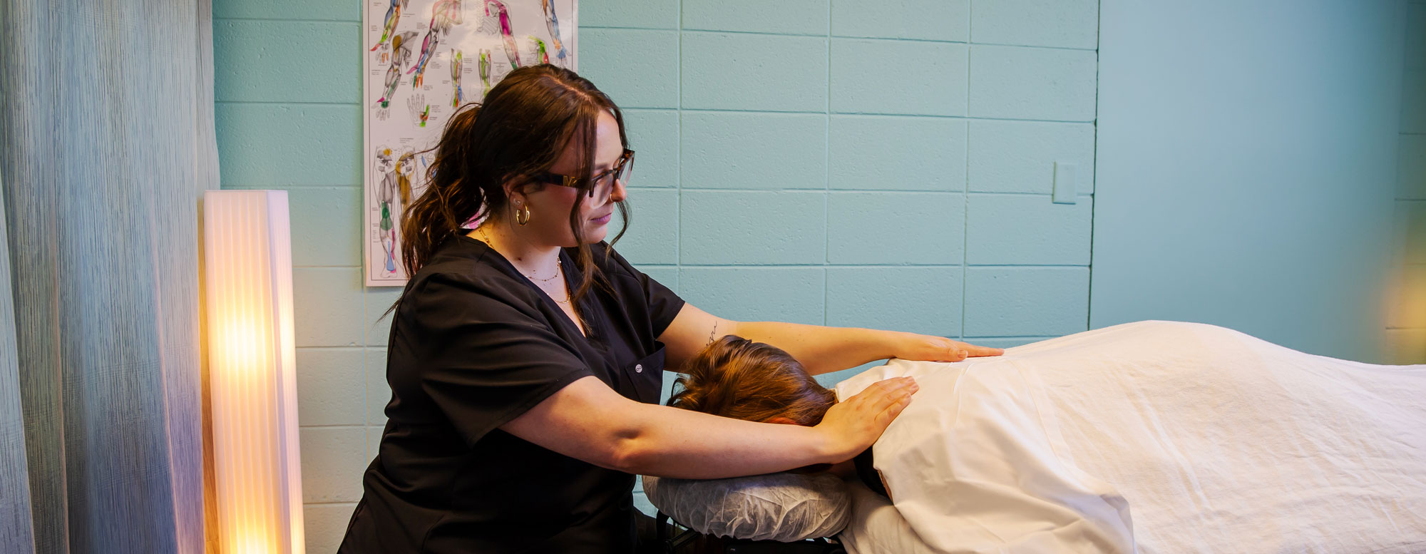 Student practicing therapeutic massage techniques in a campus lab setting.