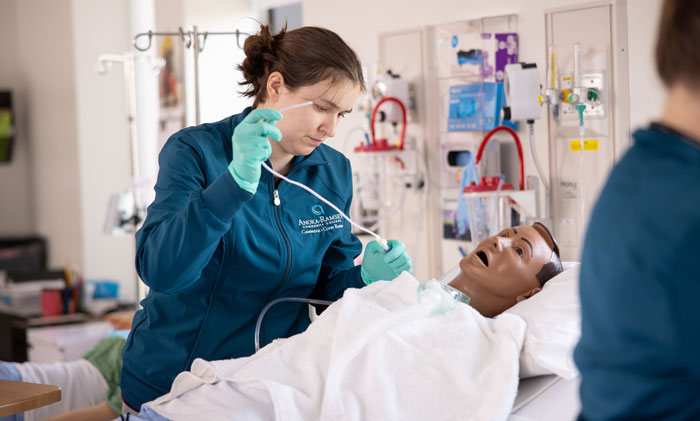 Nursing student practices patient care skills using a medical simulation mannequin