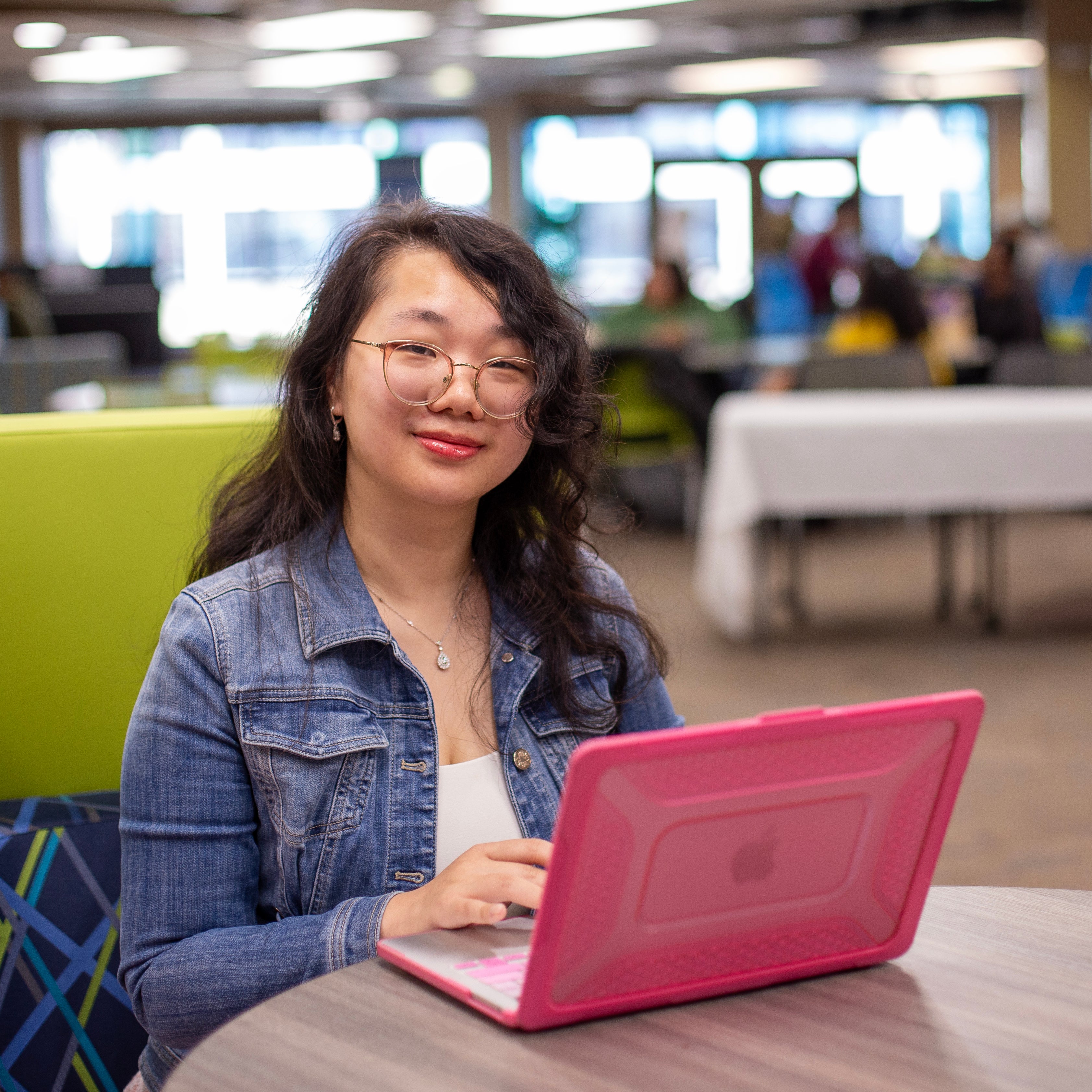 Student smiles sitting with laptop open