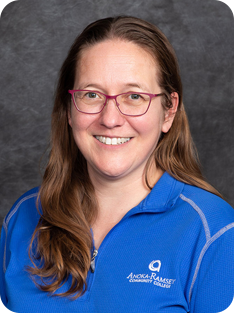 Individual smiling at camera, wearing blue shirt